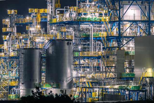 Large oil refinery lit up at night, symbolizing global energy trading